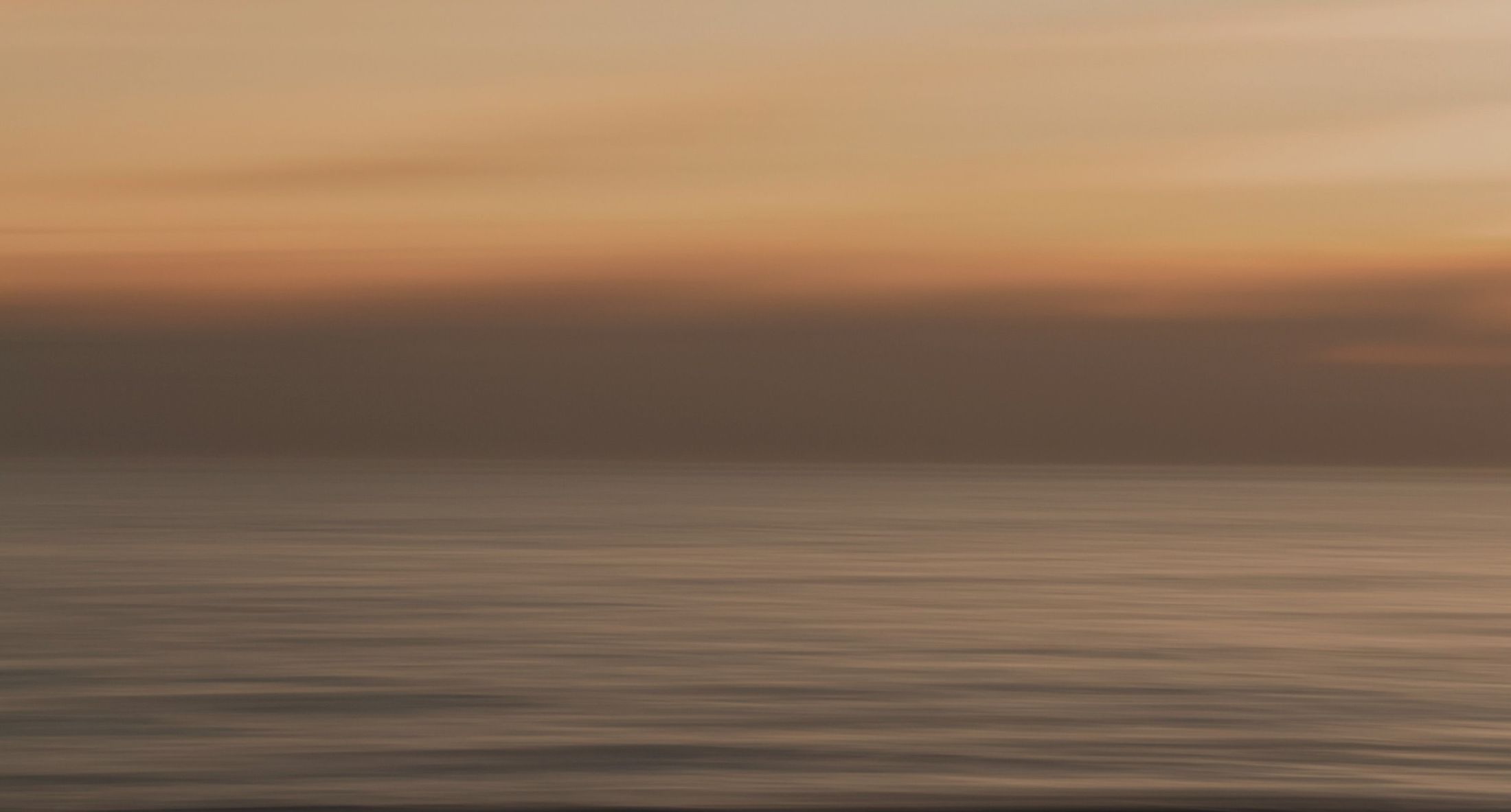 Calm ocean at sunset with soft colors.